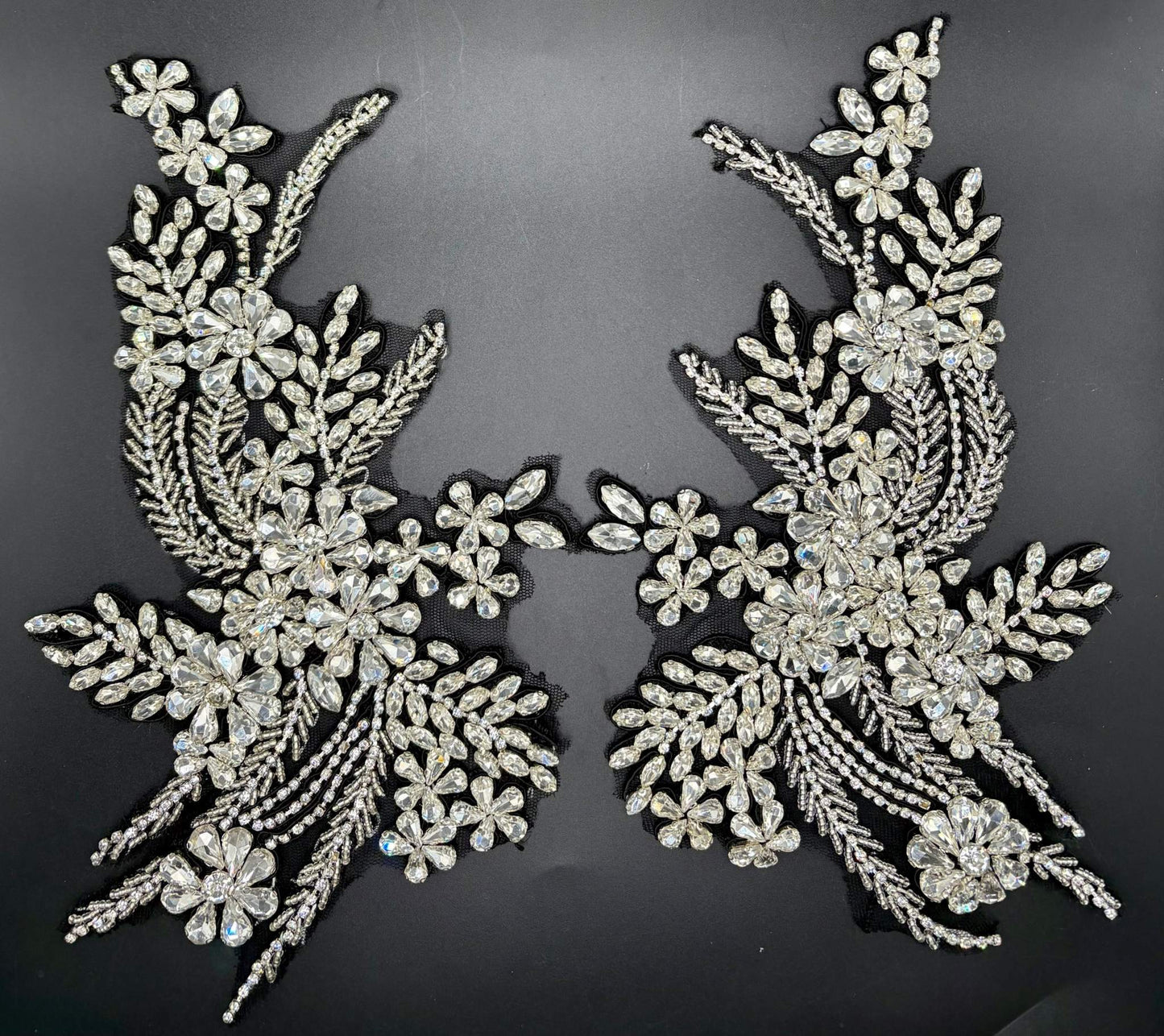 Handmade rhinestone appliqué pair on black background, intricately arranged for elegant designs.