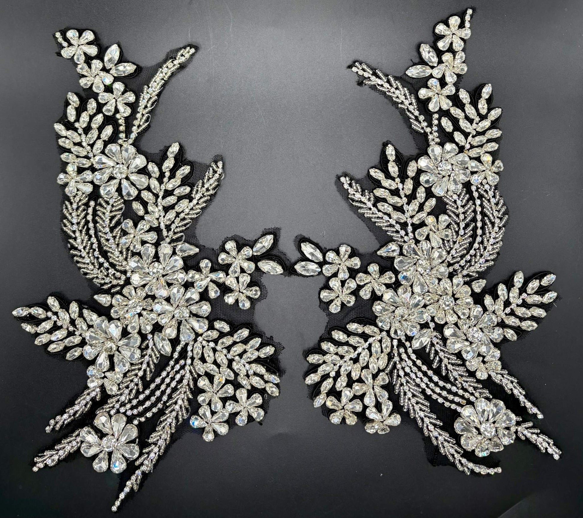 Handmade rhinestone appliqué pair on black background, intricately arranged for elegant designs.